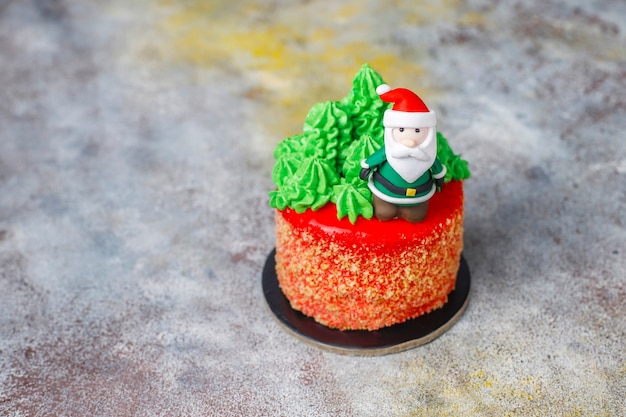 Kleine kersttaart versierd met zoete figuren van kerstboom, kerstman en kaarsen.