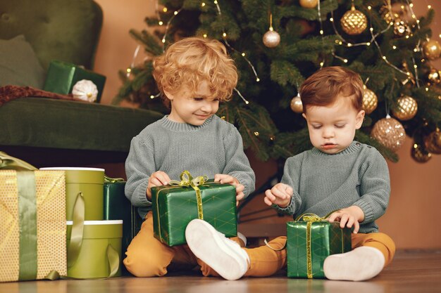 Kleine kinderen in de buurt van de kerstboom in een grijze trui