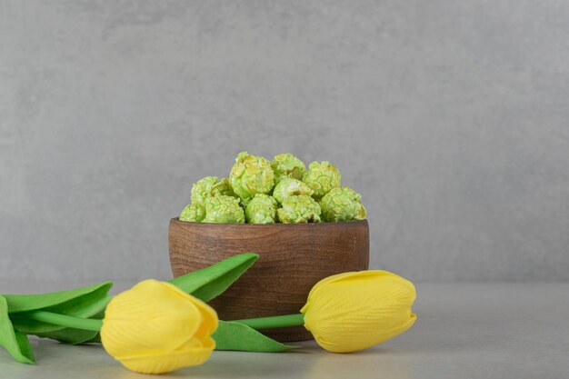 Kleine kom popcornsuikergoed en twee tulpen op marmeren achtergrond.