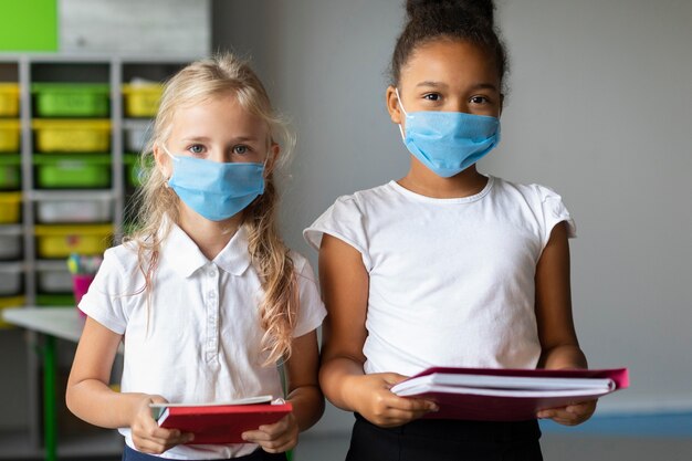 Kleine meisjes die medische maskers dragen in de klas