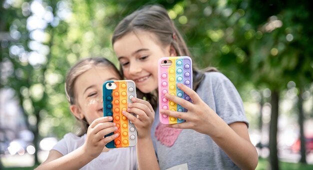 Kleine meisjes gebruiken telefoons in trendy hoesjes om tegen stress te knallen.