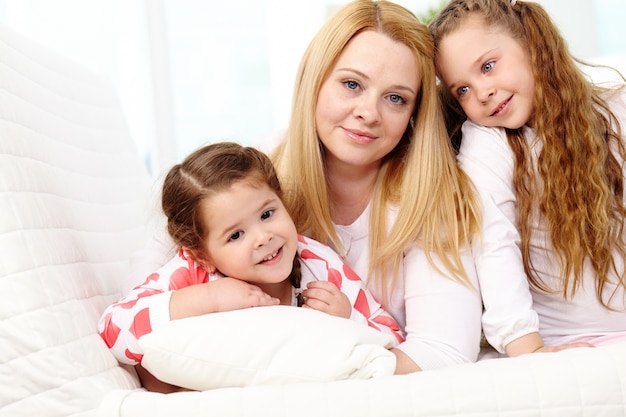 Kleine meisjes met hun moeder zittend op de bank