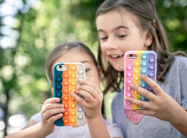 Kleine meisjes met telefoons in een hoesje met puistjes maken er een trendy anti-stress speeltje van