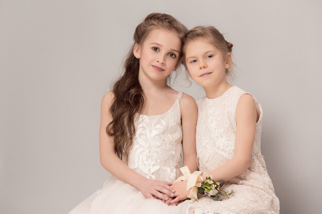 Kleine mooie meisjes met bloemen gekleed in trouwjurken