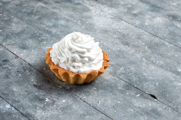 kleine romige cake heerlijk gebakken geïsoleerd op grijs bureau, cake koekje zoete suikercrème