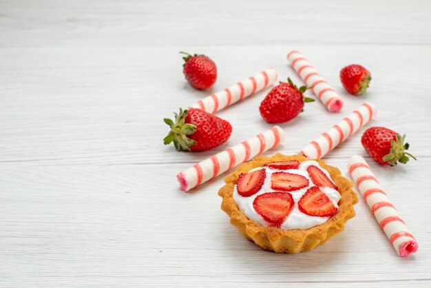 kleine romige cake met verse aardbeien en snoepjes op licht, cake zoet fruit bessen bakken