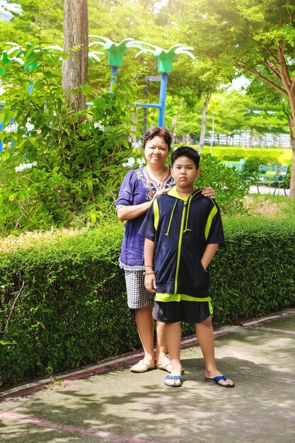 Kleine schattige Aziatische jongen met haar moeder in de tuin