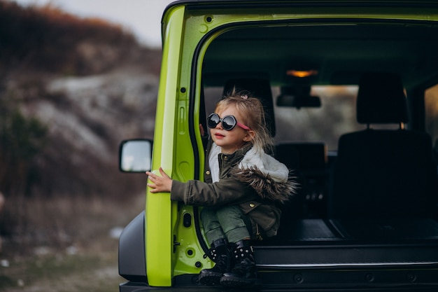 Kleine schattige baby meisje zit in de achterkant van de auto