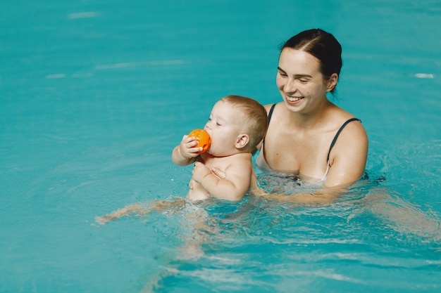 Kleine schattige babyjongen. Moeder met zoon. Familie spelen in een water