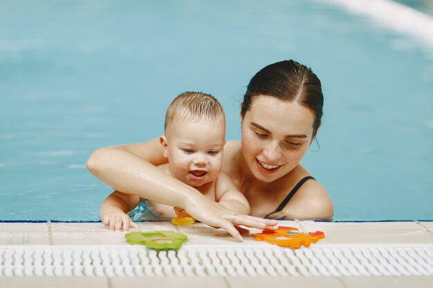 Kleine schattige babyjongen. Moeder met zoon. Familie spelen in een water