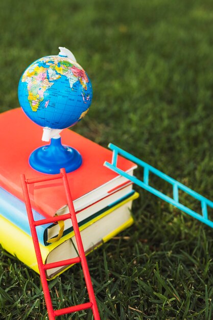 Kleine wereldbol die bovenop boekenstapel wordt geschikt