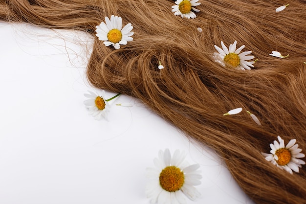 Gratis foto kleine witte bloemen liggen op de bruine haarkrullen