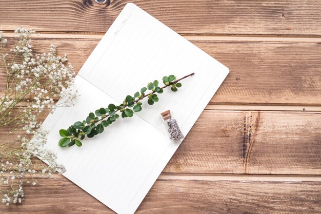 Kleine witte bloemen met stengel en lavendel bloem fles op laptop over de houten achtergrond