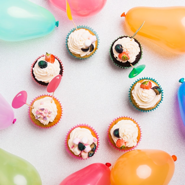 Kleine zoete cupcakes met luchtballons op lichte lijst