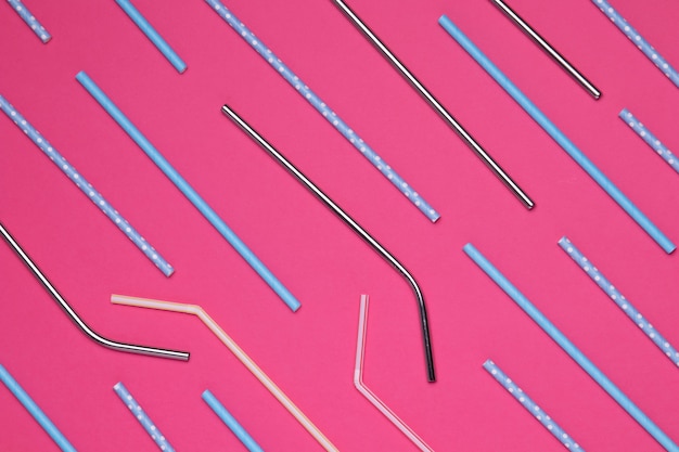 Kleurrijk papier en metalen rietjes op roze achtergrond