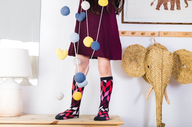 Kleurrijke ballen en harten die op koord voor meisje hangen die zich over tafelblad bevinden