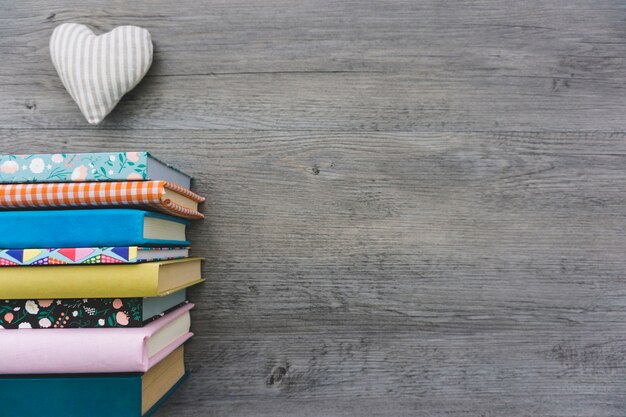 Kleurrijke boeken en hart op houten oppervlak