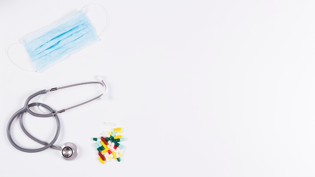 Kleurrijke capsules; stethoscoop en masker op witte achtergrond