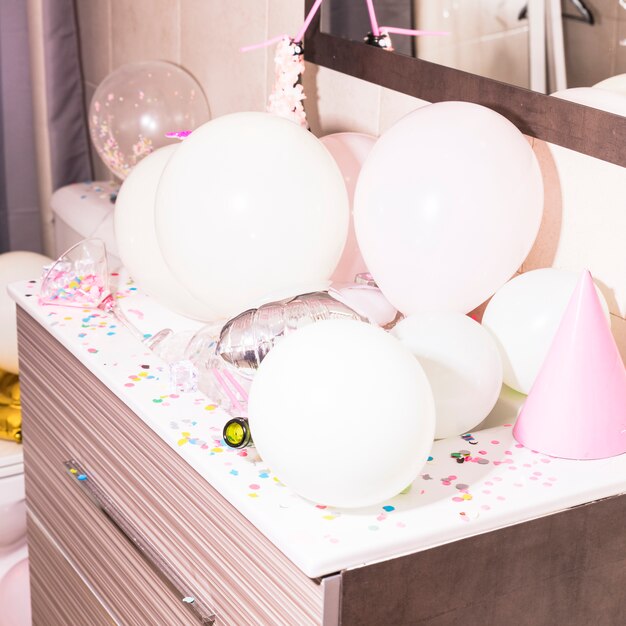 Kleurrijke confetti en witte ballonnen op houten bureau