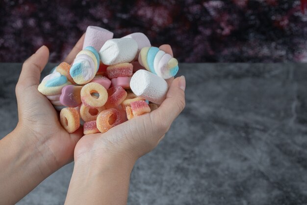 Kleurrijke marshmallows en jellybeans in de hand van een man.