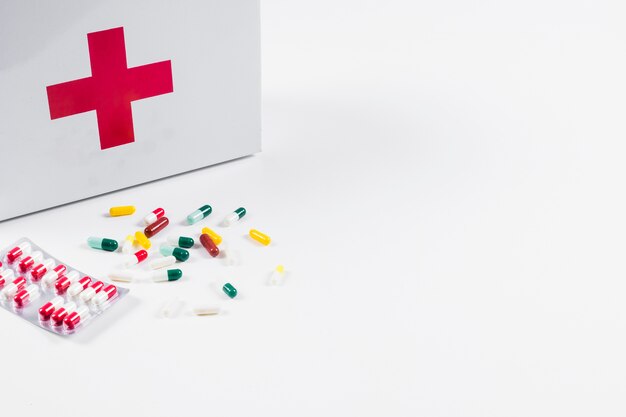 Kleurrijke pillen met eerste hulpuitrusting die op witte achtergrond wordt geïsoleerd