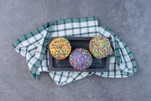 Kleurrijke pralines versierd met hagelslag op zwarte plaat.