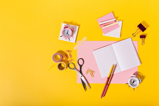 Kleurrijke samenstelling van vrouwelijke kantoorbehoeften in roze kleuren die op oranje muur liggen