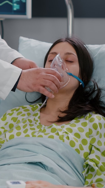 Gratis foto klinisch team dat patiënt bewaakt die zuurstofmasker zet en ademhalingstoestand analyseert tijdens respiratoire noodsituatie op ziekenhuisafdeling