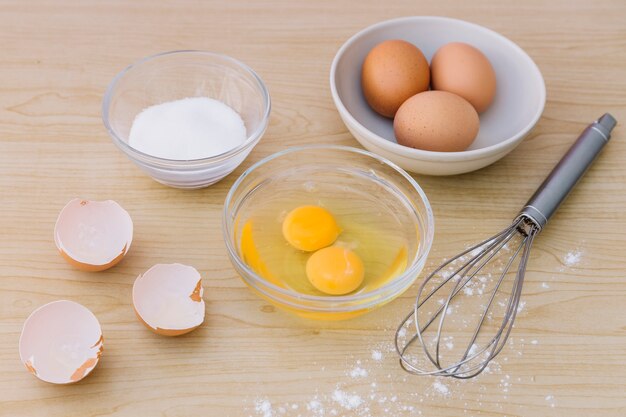 klop; eieren en eierdooier met schelpen en meel voor het bakken cake op houten bureau