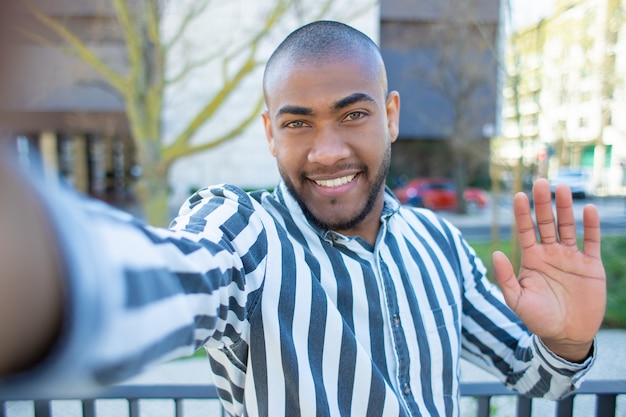 Knap lachende Afro-Amerikaanse man zwaaien