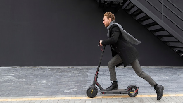 Knap mannetje dat een elektrische autoped berijdt