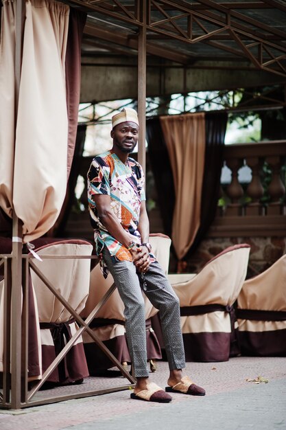 Knappe Afro-Amerikaanse man met traditionele kleding en pet in moderne stad