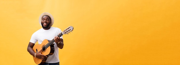 Knappe Afro-Amerikaanse retro stijl gitarist akoestische gitaar spelen geïsoleerd op gele achtergrond