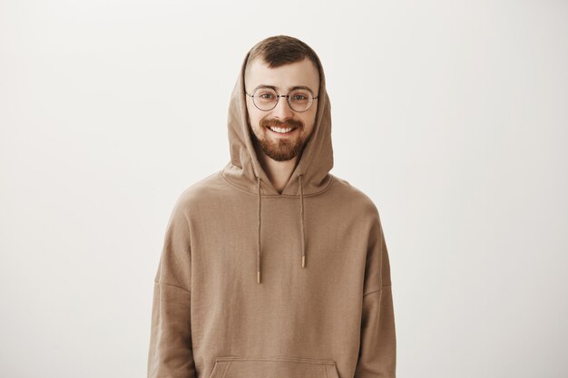 Knappe bebaarde hipster man in hoodie en glazen glimlachen
