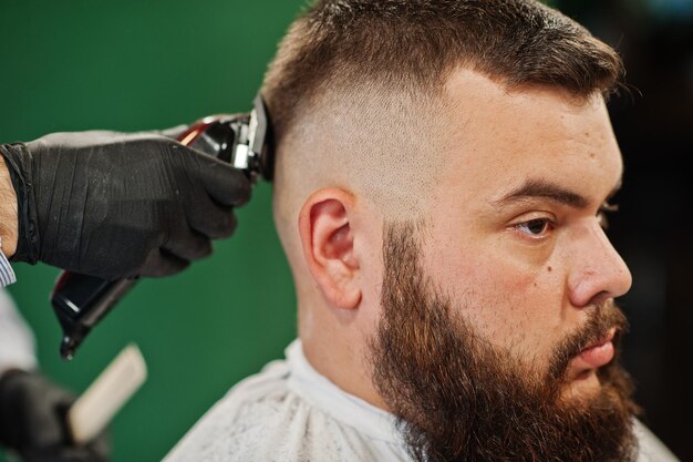 Knappe bebaarde man bij de kapperszaak kapper op het werk