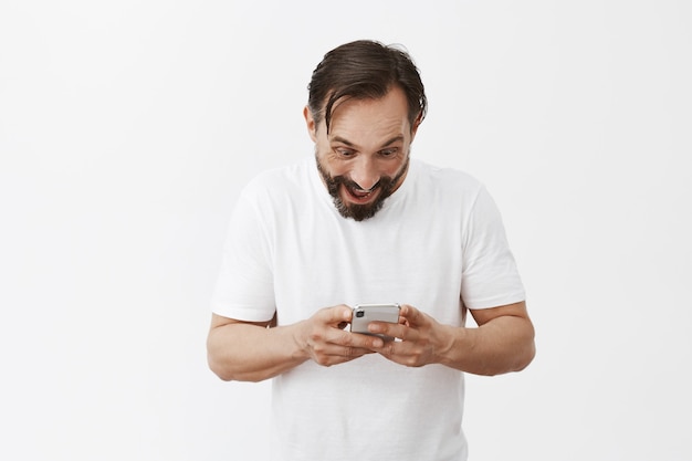 Knappe bebaarde volwassen man poseren met zijn telefoon