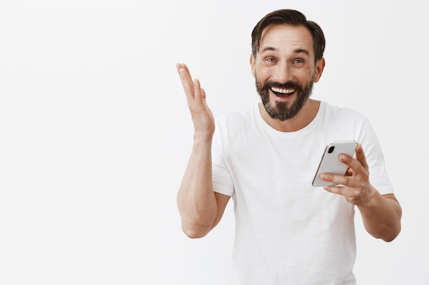 Knappe bebaarde volwassen man poseren met zijn telefoon