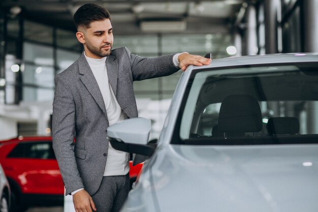 Knappe bedrijfsmens die een auto in een autoshowroom kiest