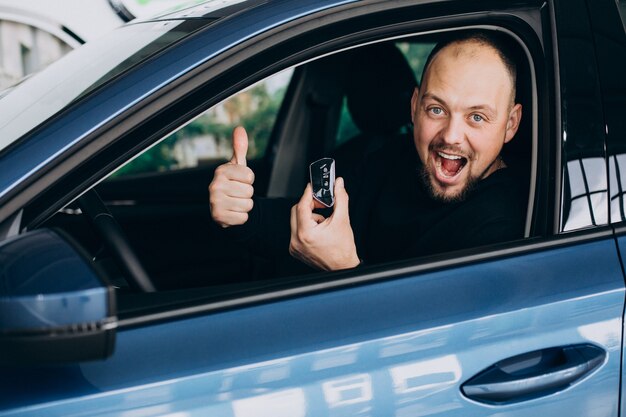 Knappe bedrijfsmens die een auto in een autoshowroom kiest