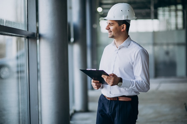 Knappe bedrijfsmenseningenieur in bouwvakker in een gebouw