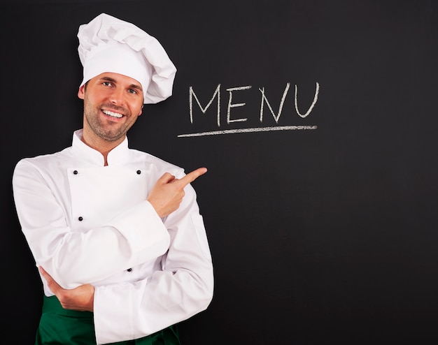 Knappe chef-kok die menu toont