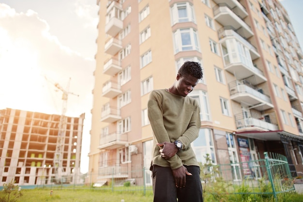 Knappe en aantrekkelijke Afro-Amerikaanse man poseren naast het hoge gebouw op straat