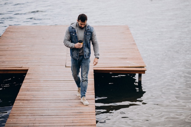 Gratis foto knappe gebaarde mens die koffie drinken door de rivier in park