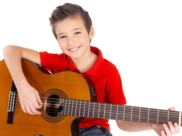 Knappe gelukkige jongen speelt op akoestische gitaar op wit wordt geïsoleerd