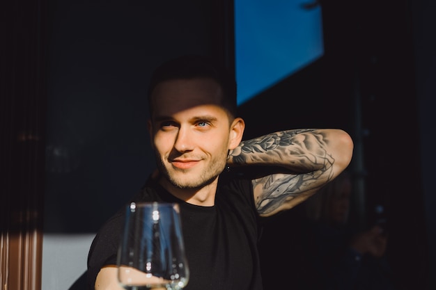 Knappe getatoeëerde man op een zomerterras in een stadscafé drinken wijn. street cafe.