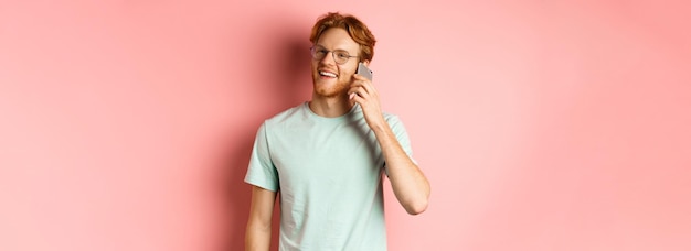 Knappe hipster man met rood haar en baard praten op mobiele telefoon iemand bellen en hap kijken