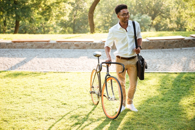 Knappe jonge Afrikaanse man met fiets buitenshuis