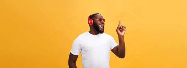 Knappe jonge afro-amerikaanse man luisteren en lachen met muziek op zijn mobiele apparaat geïsoleerd o