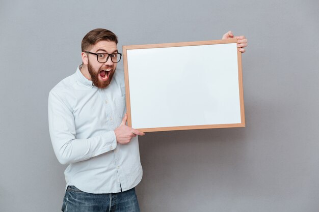 Knappe jonge bebaarde zakenman bedrijf leeg bord