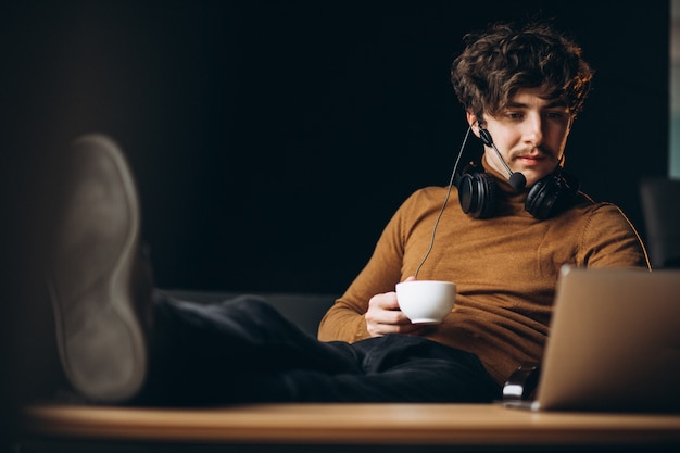 Knappe jonge bedrijfsmens die aan computer werkt en koffie drinkt